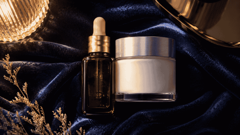 Amber retinol serum beside frosted ceramide moisturiser jar on navy velvet — ceramides and retinol together as essential companions for mature skin barrier repair