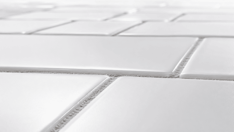 Abstract white tile surface showing brick-and-mortar grout lines — visual metaphor for the ceramides skin barrier structure in the stratum corneum