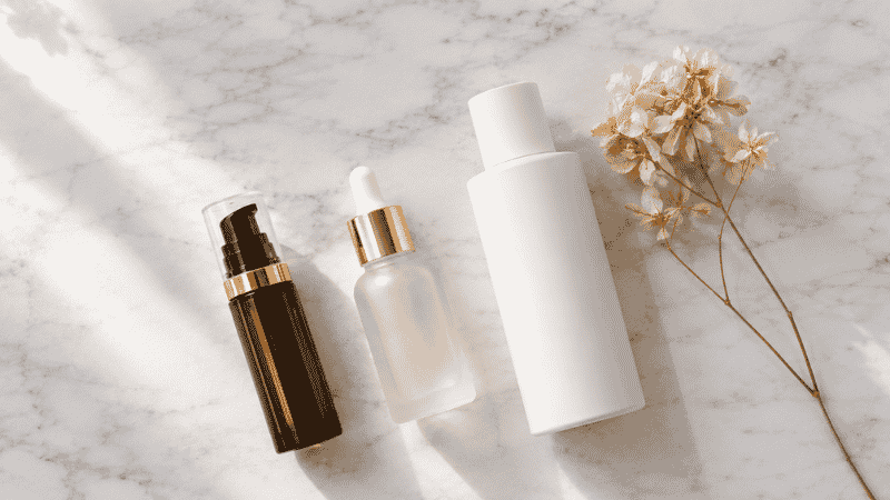 Luxury retinol serum, peptide vial and glycolic acid toner on marble — skincare ingredients to reduce forehead wrinkles and fine lines