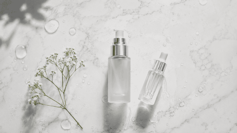 Luxury hyaluronic acid serum in frosted glass bottle with water droplets on white marble — hyaluronic acid moisturizer guide for mature aging skin