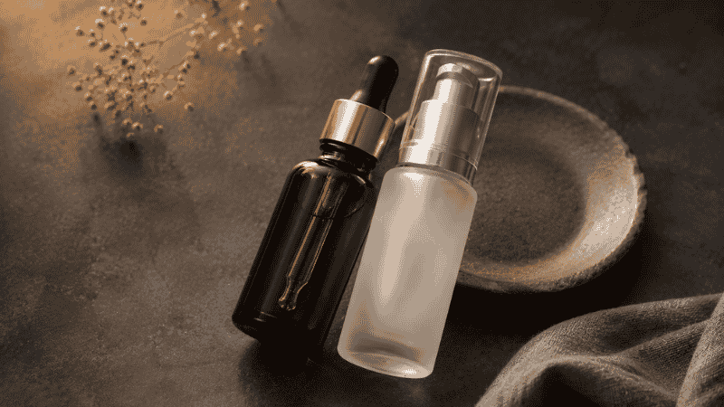 Amber retinol serum beside frosted niacinamide serum leaning together — niacinamide and retinol together as complementary actives for mature skin