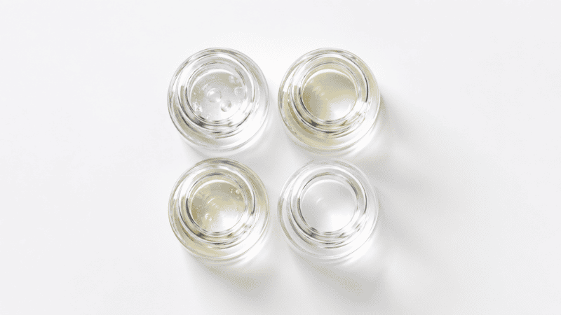 Four glass vials representing the four mechanisms of niacinamide skincare — barrier repair, brightening, antioxidant activity and NAD+ replenishment