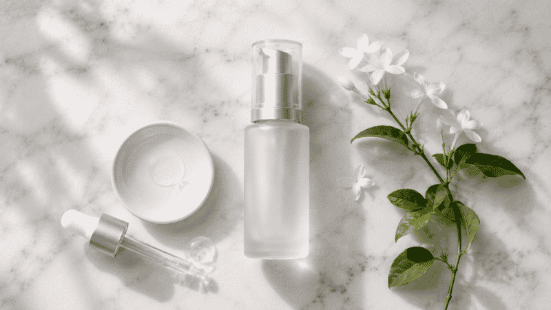 Luxury niacinamide serum in frosted glass bottle on white marble with jasmine — niacinamide skincare guide for mature aging skin