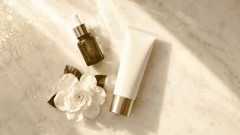Luxury mineral sunscreen tube with vitamin C serum on warm marble — titanium dioxide sunscreen for anti-aging mature skin