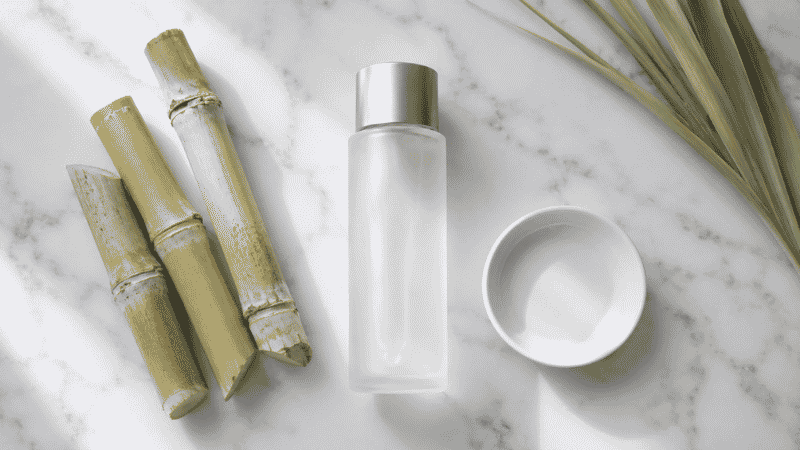 Luxury glycolic acid toner in frosted glass bottle beside sugarcane on white marble — glycolic acid toner complete guide for mature aging skin