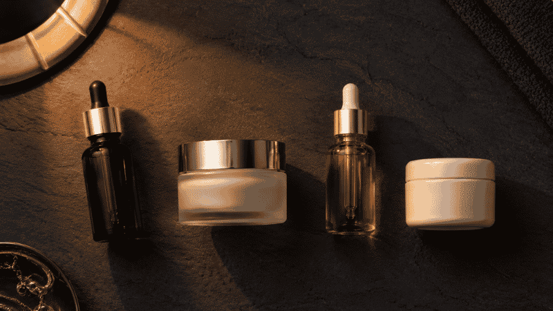 Four luxury evening skincare products including retinol, ceramide and squalane on dark slate — evening skincare routine for women over 40 focused on repair and collagen stimulation